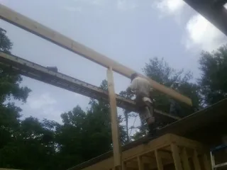 Carpenter setting a ridge beam over a new addition frame — Ice Dam Removal by Roofing Brothers in Camillus