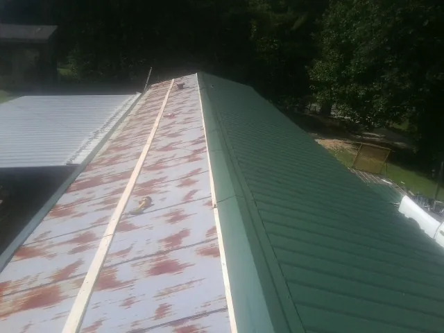 Old rusted panels beside newly installed green metal roofing — Wind Damage Roof Repair by Roofing Brothers in Camillus