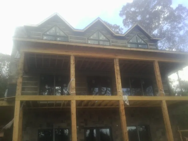Dormers and porch framing on a large log home under construction — Roof Coating work by our crew in Camillus
