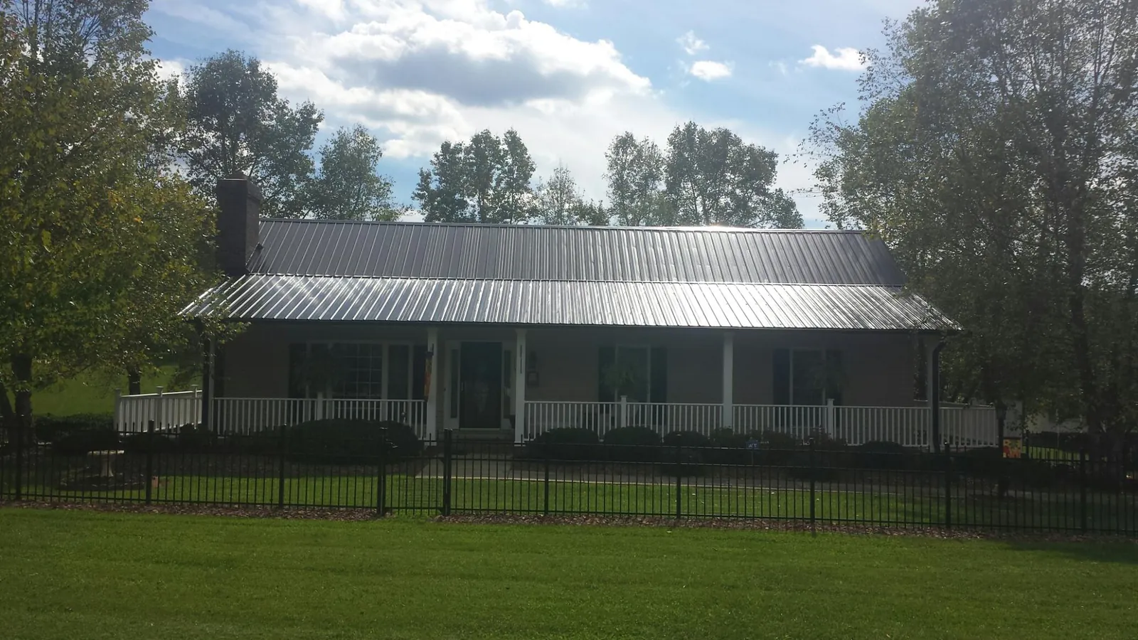 Gray metal roof on a brick ranch with a full width front porch — Gutter Guard Installation work by our crew in Camillus