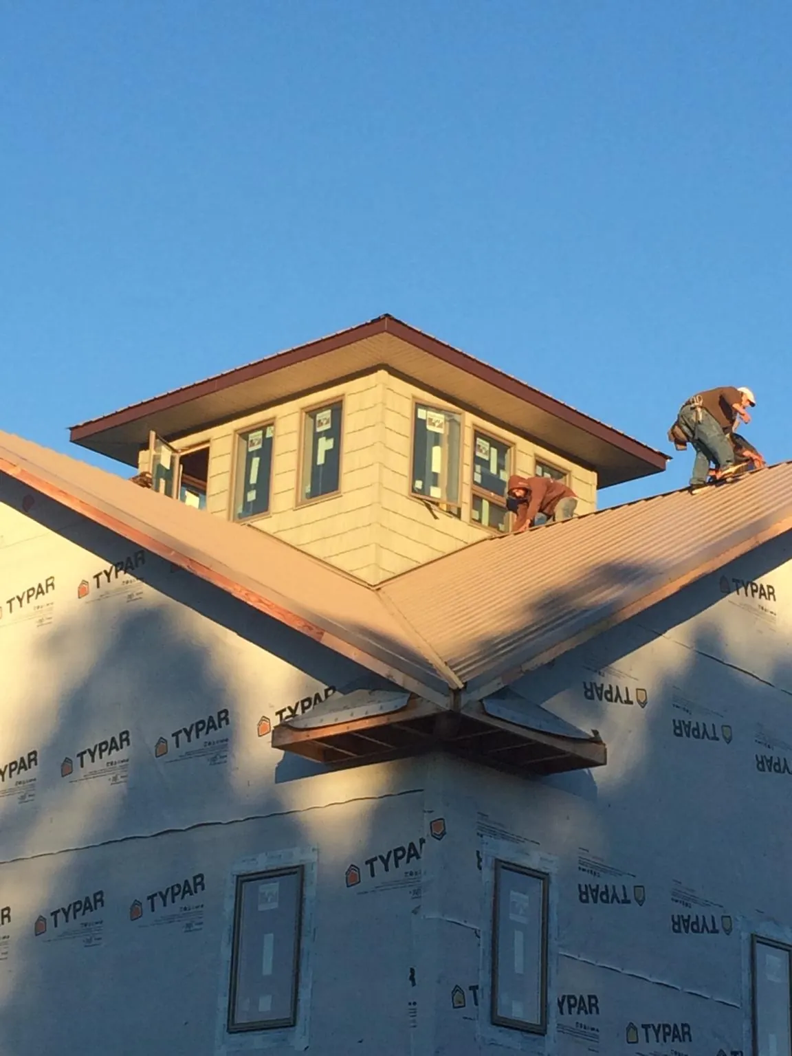 Roofers working around a rooftop cupola on a new metal roof at sunset — Roof Waterproofing in Camillus by Roofing Brothers